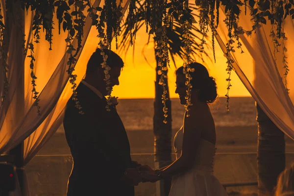 花のあるアーチの夕焼け空に恋をするカップル — ストック写真