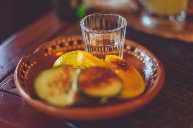 Mezcal Meksika damıtılmış alkollü içecek genellikle portakal ya da limonla, limon dilimleri ve solucan tuzu, sadece mavi agave ile yapılan tekilanın aksine, her türlü agave 'den yapılır.