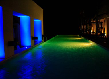 Farklı renk ışıkları olan bir havuzun gece fotoğrafı.