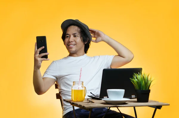 年轻的亚裔男子在暑期工作时自拍黄色背景 — 图库照片