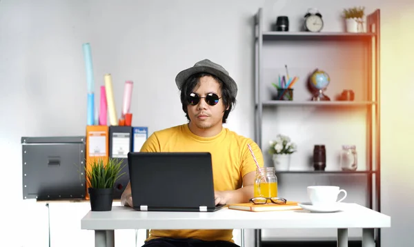 年轻男子与笔记本电脑穿着软呢帽帽子在暑假的办公室 — 图库照片