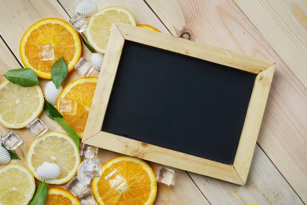 Black Board Orange Leaves Cube Ice Sea Shells Citrus Pattern on Wooden Background Copy Space