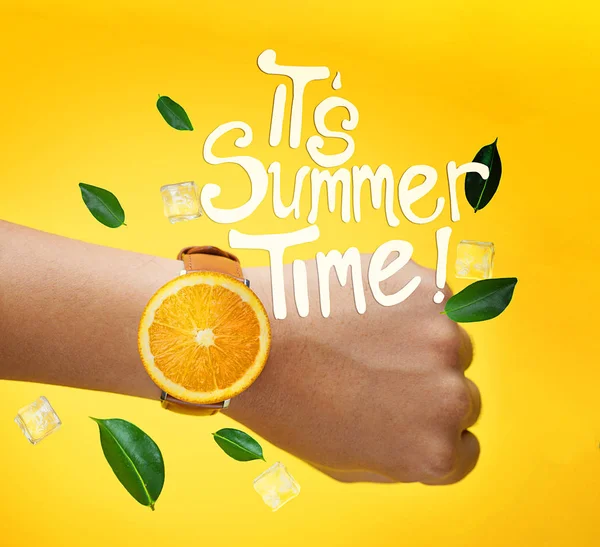 夏の時間のタイポグラフィです 男性の手を着てフルーツ オレンジ時計緑葉し アイス キューブが黄色の背景上を飛び回る — ストック写真