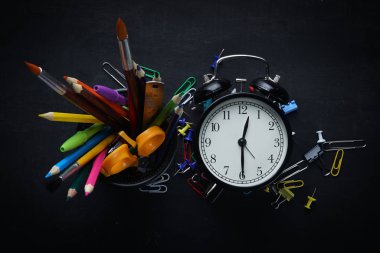 Çalar saat ve yazı tahtası üzerinde okul kırtasiye