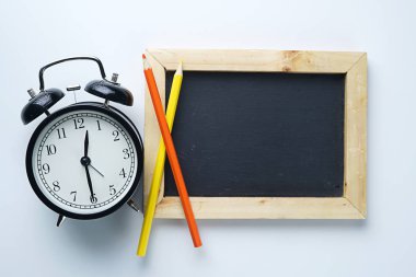 Çalar saat, renkli kalem ve yazı tahtası beyaz arka plan üzerinde