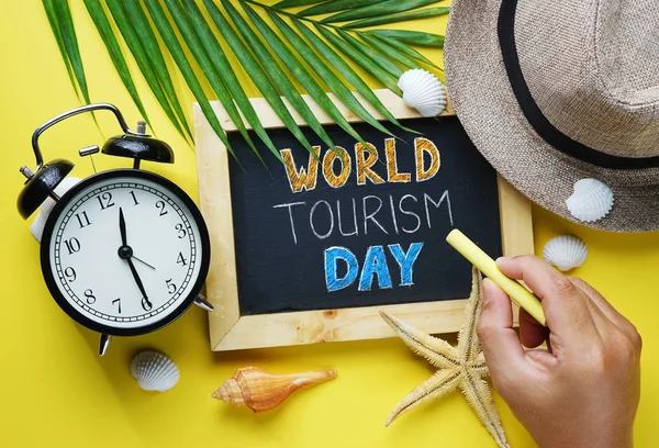 World Tourism Day Typography. Hand Holding Yellow Chalk and Blackboard