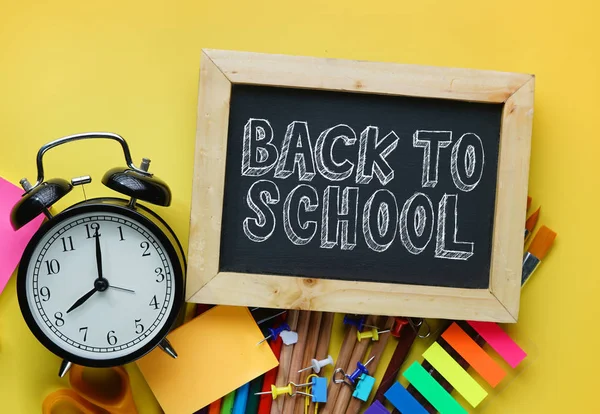 Back to School Text. Alarm Clock, Blackboard and School Stationary on Yellow Background