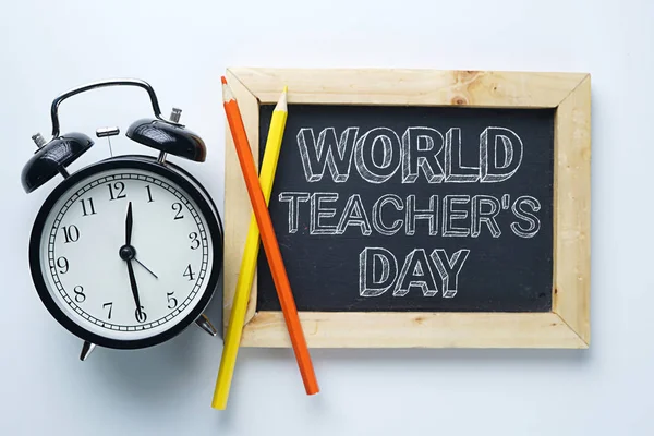 World Teacher\'s Day Text. Alarm Clock, Color Pencil and Blackboard on White Background