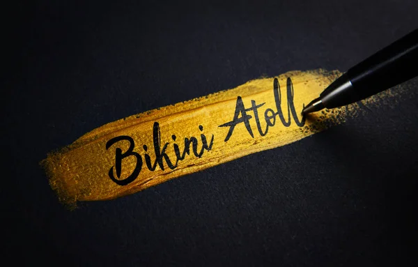 Bikini Atoll Handwriting Text on Golden Paint Brush Stroke