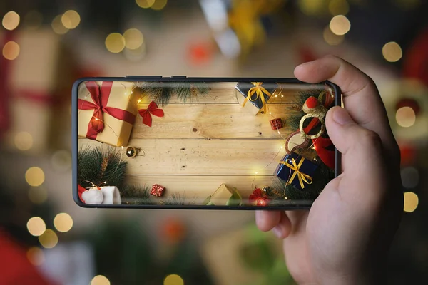 Hand Taking Picture of Christmas Decoration With Infinite Display Smartphone