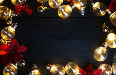 Işık Ampüller ve siyah ahşap üzerine kırmızı Atatürk çiçeği. Üstten görünüm kopya alanı