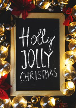 Holly Jolly Noel tipografi üzerinde Blackboard arasındaki Işık Ampüller ve siyah ahşap üzerine kırmızı Atatürk çiçeği