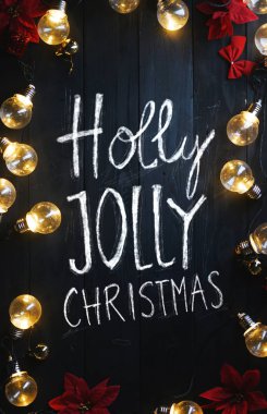 Holly Jolly Noel tipografi ampulleri ve siyah ahşap üzerine kırmızı Atatürk çiçeği