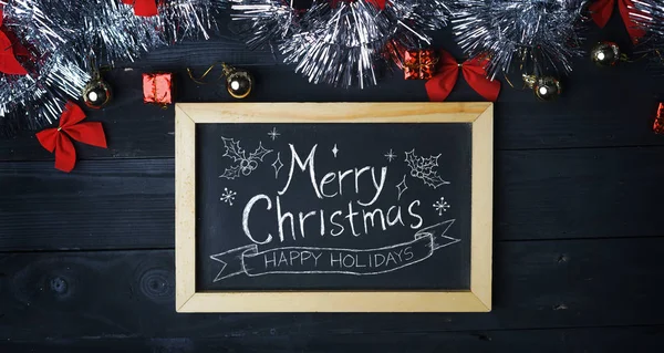 在黑板上圣诞快乐的排版 黑色木木板上的银色圣诞装饰品 — 图库照片