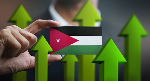 Nation Growth Concept, Green Up Arrows - Businessman Holding Card of Jordan Flag