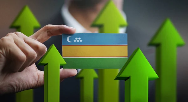 Nation Growth Concept, Green Up Arrows - Businessman Holding Card of Karakalpakstan Flag