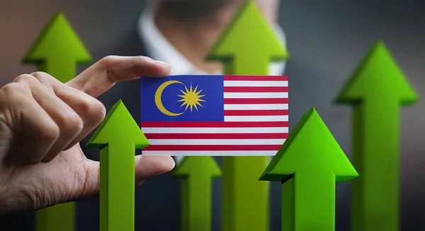 Nation Growth Concept, Green Up Arrows - Businessman Holding Card of Malaysia Flag