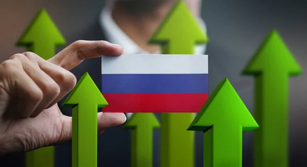 Nation Growth Concept, Green Up Arrows - Businessman Holding Card Russia Flag