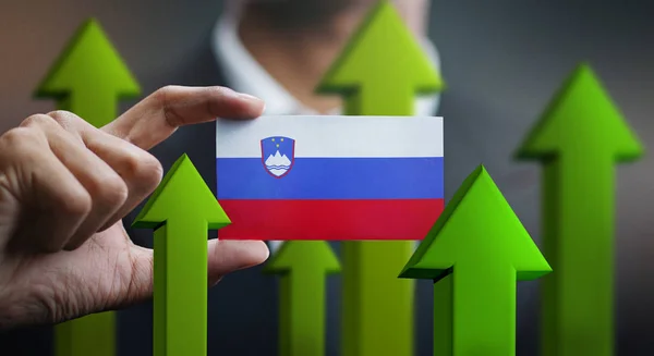 Nation Growth Concept, Green Up Arrows - Businessman Holding Card of Slovenia Flag