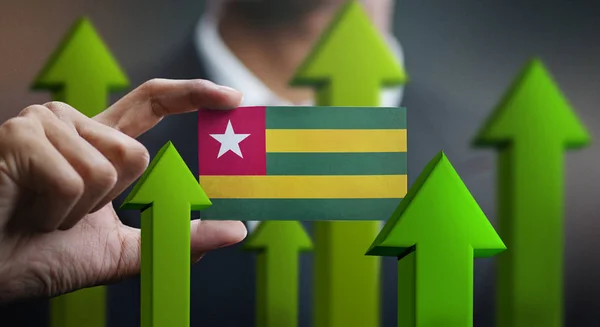 Nation Growth Concept, Green Up Arrows - Businessman Holding Card of Togo Flag