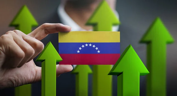Nation Growth Concept, Green Up Arrows - Businessman Holding Card of Venezuela Flag