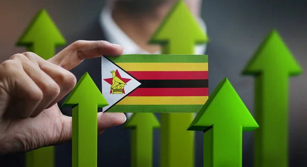 Nation Growth Concept, Green Up Arrows - Businessman Holding Card of Zimbabwe Flag