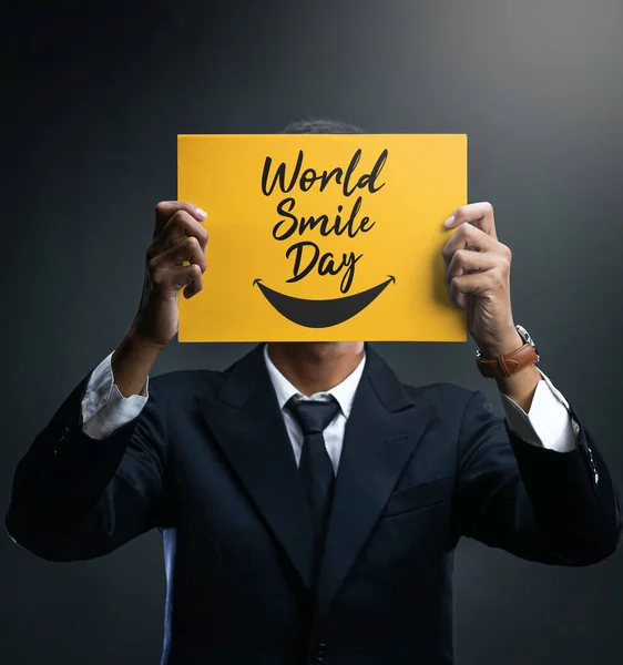 Biznesmen Trzymając World Smile Day Żółty Plakat Zakrywający Jego Twarz — Zdjęcie stockowe
