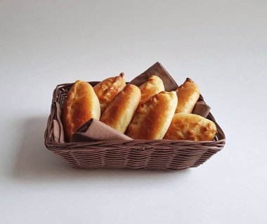 Bir sepet içinde geleneksel Rus pişmiş turta pirozhki (köfte) . Altın bir kabuk ile Ruddy maya çörekler. Beyaz arka plan. Izole. Börekler lahana, elma, yumurta, çilek, meyve, et ile pişirilebilir