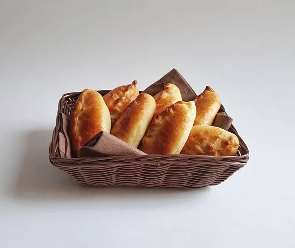 Bir sepet içinde geleneksel Rus pişmiş turta pirozhki (köfte) . Altın bir kabuk ile Ruddy maya çörekler. Beyaz arka plan. Izole. Börekler lahana, elma, yumurta, çilek, meyve, et ile pişirilebilir