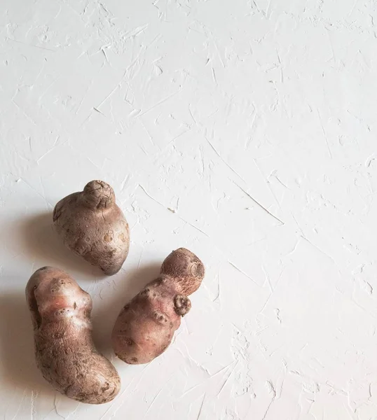 Kopya spazile ile açık gri arka plan üzerinde Olağandışı doğal patates. Trendy çirkin organik sebzeler