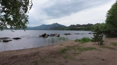 Dağların yanındaki gölün kumsalı, Borovoe, Kazakistan 'daki kayalar ve ağaçlar.