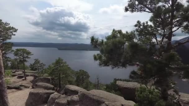 Вид на скальное озеро с горы со скал и деревьев с лентами желаний на ветвях — стоковое видео