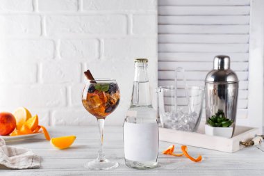 Buzlu çay, viski, çilek ve tonik ve bir yer altında metin şişesini Beyaz ahşap zemin üzerinde Bar aksesuarları ile bir şişe ile bir bardak buz ile kokteyl