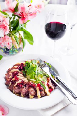Ördek göğsü ile elma ve salata şarap ve beyaz masaya çiçek yabanmersini sosu altında dilimleri ile servis. Popüler Asya gıda
