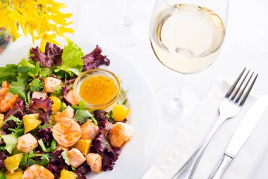Karides, marul, portakal ve mangolu sağlıklı salata. Beyaz şarap ile portakal hardal soslu bir tabakta servis ediliyor.