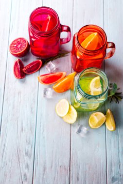 Üç renkli gözlük narenciye limonata ve meyve mavi bir arka plan üzerinde bir dilim ile. Düz kopya alanı ile yatıyordu