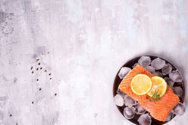 Limon dilimi taş zemin üzerine ahşap plaka üzerinde somon biftek buz üzerinde. Balık gıda kavramı. Kopya alanı ile üstten görünüm
