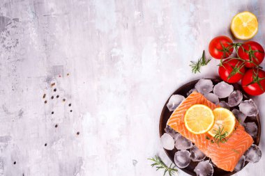 Somon biftek buz limon dilimi ve bir taş üzerinde ahşap plaka üzerinde domates ile ışık arka plan. Balık gıda kavramı. Kopya alanı ile üstten görünüm