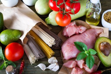 İtalyan spagetti, ham soba erişte ve ya bir grup, çiğ et, avokado, kabak domates eski bir ahşap zemin ile tavuk, lay soymak. Ev yapımı yemek kavramı