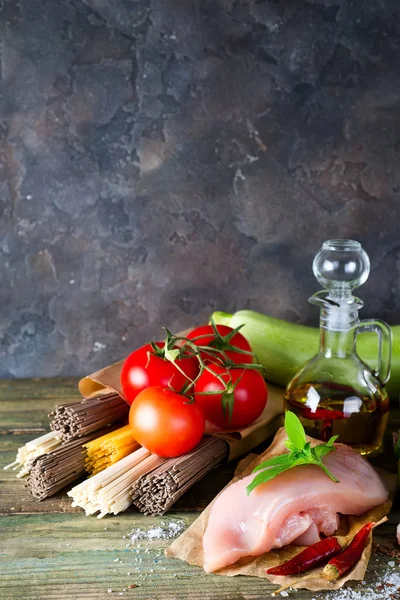 イタリアのスパゲティ 生そば Comen 鶏の生肉 古い木製の背景にトマトとアボカド ズッキーニ 領域をコピーします 自家製の料理のコンセプト — ストック写真