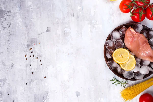 Tavuk ile İtalyan makarna ve limon dilim, pişmemiş makarna ve buz beton zemin üzerine domates yemek pişirmek için malzemeler. Metin için yer kopyalayın ve yat