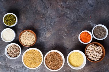 Kase superfoods ve tahıllar seçiminde: quinoa, chia, karabuğday, fasulye, nohut, Kuskus Kuskus, bulgur, mercimek, keten tohumu, yabani pirinç gri beton zemin üzerine. Düz kopya alanı ile yatıyordu