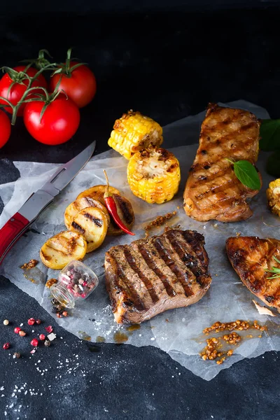 Üç çeşit kağıt üzerinde karanlık bir arka plan üzerinde ızgara et tavuk, domuz eti ve domates ve Mısır ile sığır eti, baharat. Düz yatıyordu
