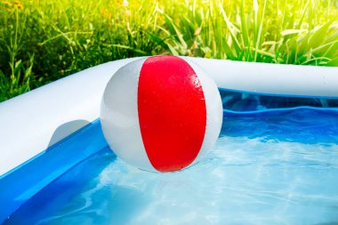 Bahçedeki yüzme havuzunda yüzen top. Yaz tatillerini, rahatlama ve eğlenceli güneş için kavram