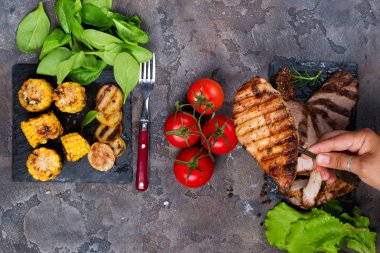 bir çatalla biftek ızgara biftek ıspanak, domates ve kopya alanı, düz taş zemin üzerine ızgara patates ile kayrak plaka üzerinde taze üç tür arka plan üzerinde yatıyordu el tutar