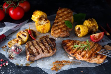 Çam dilim ve tavuk biftek, domates, Mısır ve patates bir ızgara Fesleğenli ve biberiye siyah bir beton zemin üzerine ızgara. Düz kopya alanı ile yatıyordu