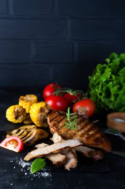 Çam dilim ve tavuk biftek, domates, Mısır ve patates bir ızgara Fesleğenli ve biberiye siyah bir beton zemin üzerine ızgara. Düz kopya alanı ile yatıyordu