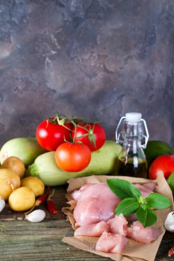 Bir demet İtalyan spagettisi, çiğ soba eriştesi, çiğ tavuk eti, ahşap arka planda domatesli avokado, fotokopi alanı ile derisi yüzülmüş. Ev yapımı yemek pişirme kavramı
