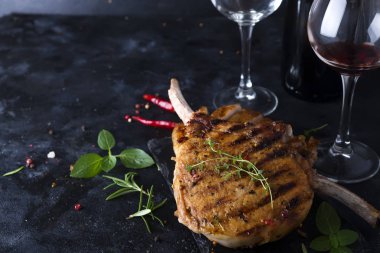 Baharatlar ve bir bardak ve bir şişe şarap siyah mermer zemin üzerine kızarmış kuzu kaburga.