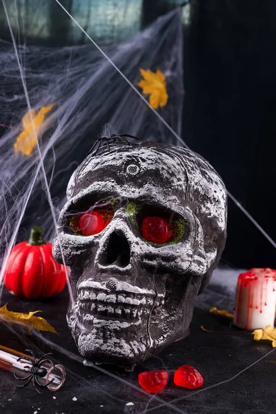 Happy Halloween Party Table with spider web, skull and candy and burning candles against spider web background.